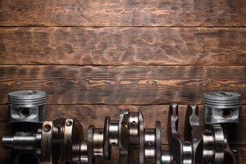 Wall Mural - Old car crankshaft and engine pistons on the wooden workbench flat lay background with copy space.