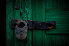 Closeup Of An Old Wooden Green Door With A Rusted Metal Lock On It