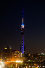 Sky Tower At Night In Auckland, New Zealand By The Light Of Nightly Skyscrapers.