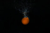 Fototapeta Łazienka - Fresh orange falling in water with splash on black background