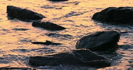 Wall Mural - Relaxing nature scene of sea waves calm splash on wet rocks at sunset