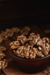 Sticker - Walnuts close up in a brown bowl on a dark wooden background. Organic food concept.