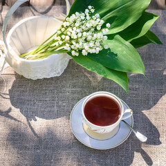 Poster - Bouquet of lilies of the valley in a beautiful white basket and a cup of tea