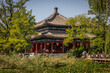 Ein alter kaiserliche Pavillon in traditionellem chinesischen Baustil mit roten Säulen unter Trauerweiden im schönen Naturpark des alten Sommerpalastes in Peking auf einem See