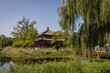 Ein alter kaiserliche Pavillon in traditionellem chinesischen Baustil sowie ein Steg unter grünen Trauerweiden im schönen Naturpark des alten Sommerpalastes in Peking