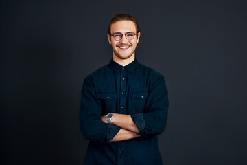 Be prepared to stand out in business. Cropped portrait of a handsome young businessman standing alone with his arms folded against a black background in the studio.