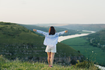 Wall Mural - Woman standing with arms up on the mountain. Successful woman hiking with open arms on top mountain. 