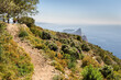 Sentier côtier sur une falaise au bord de la méditerranée avec au loin un rocher en forme de bec. La Ciotat vers le Cap Canaille et Bec de l'Aigle
