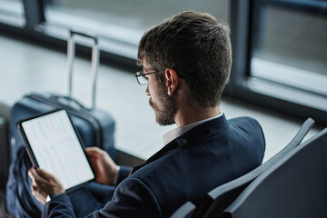 businessman using a digital tablet while sitting on a bench in t