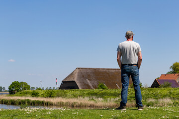 Wall Mural - Senior man with cap enjoying the view at island and nature reserve Tiengemeten Hoeksche Waard n South Holland in The neteherlands