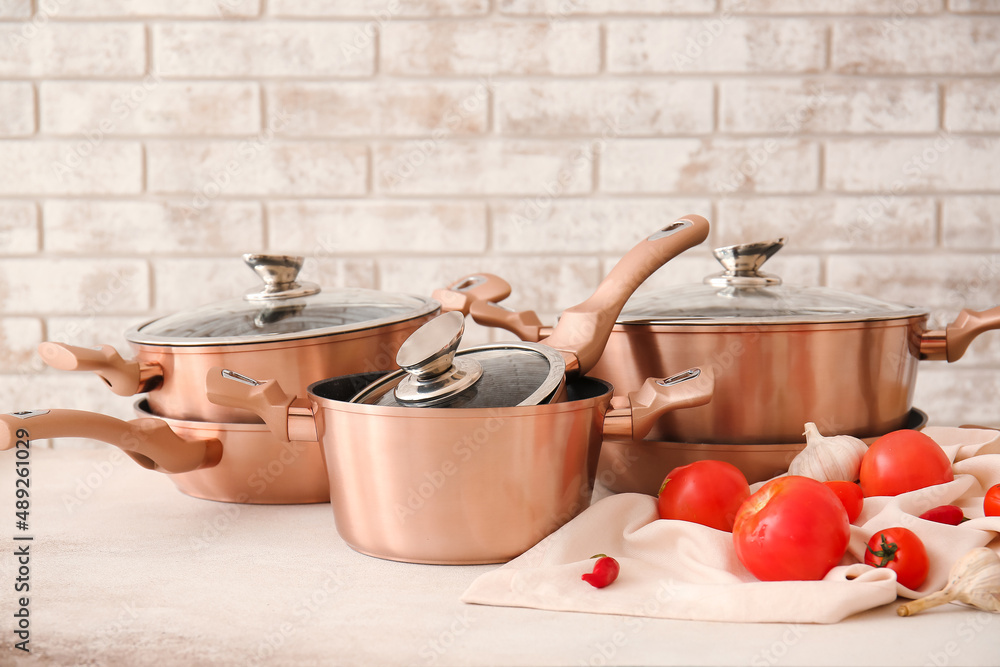 Set of kitchen utensils and vegetables on table against brick background
