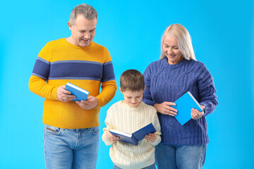 Wall Mural - Little boy with his grandparents in warm sweaters reading books on blue background