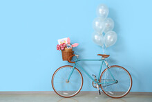 Bicycle With Baskets, Tulips, Easter Eggs,  Greeting Card And Balloons Near Blue Wall