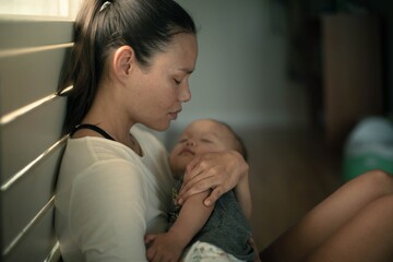 a sad exhausted mother home alone with her baby. postpartum depression.