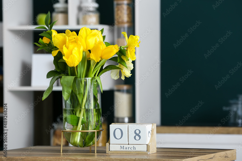 Vase with tulips and cube calendar with date 8 MARCH on wooden table. International Women's Day celebration
