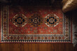 directly above view of small patterned middle eastern rug on wood floor with gold curtain