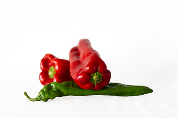 Two red peppers, on a green Italian pepper on a white background