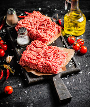 Raw Minced Meat On A Cutting Board With Cherry Tomatoes. On A Black Background. High Quality Photo