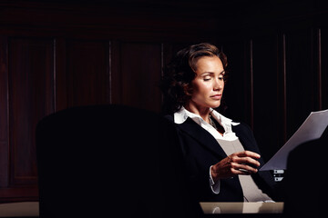 Wall Mural - Preparing legal documents. Attractive mature legal woman reading documents at a desk.