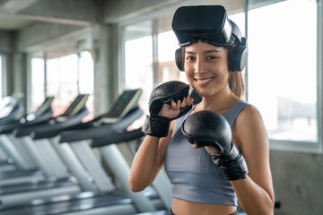 Wall Mural - Portrait of Healthy Asian athletic woman in sportswear wearing VR glasses do boxing exercise workout in virtual reality cyberspace at fitness gym. Metaverse digital entertainment technology and sport