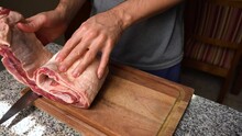 Man Rolling Up Raw Flank Meat In The Kitchen