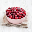 Frozen Cranberries in a Pink Bowl on a white wooden surface, side view.