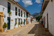 Typical cobblestone street of historic town Villa de Leyva with two story white houses in light and shadow, Colombia