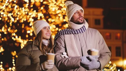 Poster - winter holidays, hot drinks and people concept - happy couple with takeaway coffee in disposable paper cups talking in city on christmas