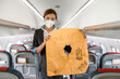 © Kostiantyn - Female flight attendant in medial mask holding life vest