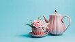 Creative layout with pink teapot and coffee cup filled with fresh flowers on pastel blue background. Creative floral spring bloom concept. Morning breakfast idea. Natural still life visual trend.