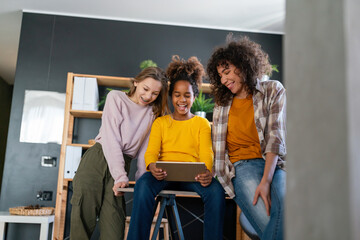 Wall Mural - Happy multiethnic teenagers holding technology gadgets using digital devices studying together.