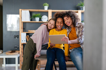 Wall Mural - Happy multiethnic teenagers holding technology gadgets using digital devices studying together.