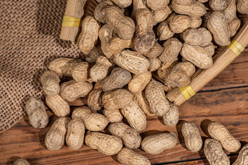 The container on the wood grain table is full of peanuts