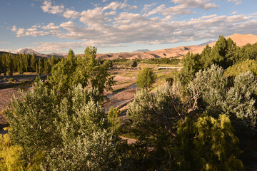 Wall Mural - Beautiful landscape of rocks, green grass, trees and creek against a blue cloudy sky on a sunny day