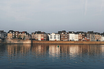 Sticker - A row of colorful cozy houses reflecting in a pond in a suburban neighborhood of Maastricht