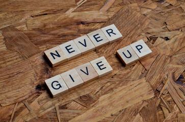 never give up text on wooden square, motivation and business quote