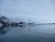 malownicze ośnieżone góry we mgle odbijające się w tafli wody w regionie svalbard na arktyce