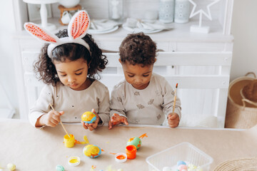 Wall Mural - Little African American boy and girl paint Easter eggs at home. black children are preparing for Easter.