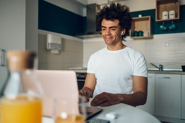 African american man using laptop in the kitchen at home