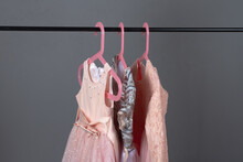 Pink And Gray Sequined Luxury Dresses For Baby Girls Hang On Hangers On A Gray Background