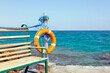 Orange life buoy, bench overlooking the sea
