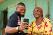 african man shows an old african woman interesting content on his phone