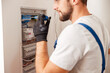 © Kostiantyn - Electrical technician in uniform installing and connecting electrical equipment in a switchboard with fuses