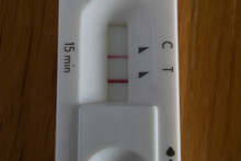 Covid rapid antigen test showing positive result on wooden table. Horizontal format close up with selective focus