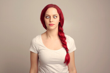 Wall Mural - close up portrait of pretty female model with red hair in a braid, expressing emotion over the top facial expression on a studio background.