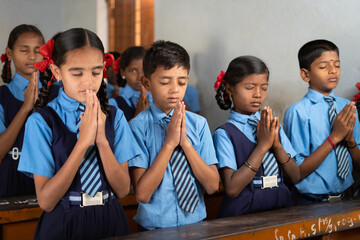 Students at classroom doing morning prayer with closed eyes - concept of wisdom, friendship, development and discipline.