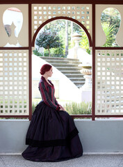 Canvas Print - Full length portrait of red-haired woman wearing a historical victorian gown costume, walking around beautiful location with  Gothic stone architecture.