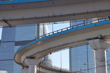 Overpasses on the background of skyscrapers. Blue sky and bright sun. Transport interchanges and urbanism.