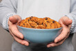A young man holds a plate with homemade cookies with raisins, chocolate, nuts. Breakfast. Close.