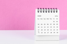 July 2022 Desk Calendar On White Table With Pink Background.